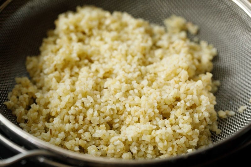 Cooked bulgur in a strainer.