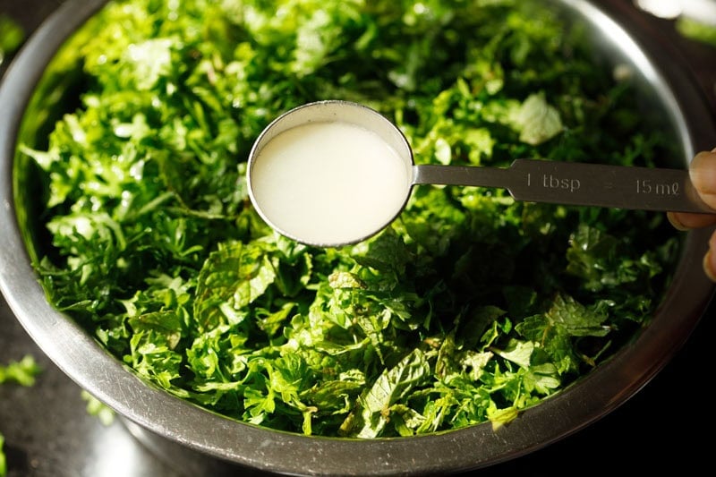 Spoon with lemon juice with parsley bowl underneath.