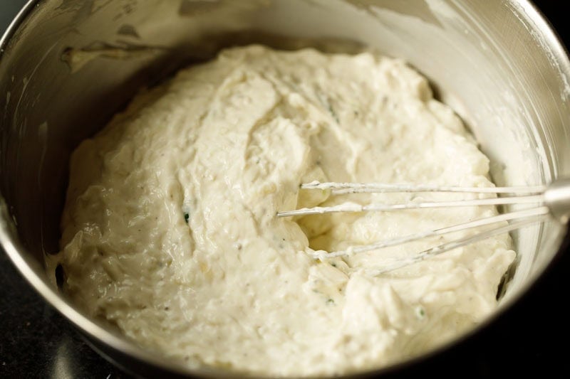 ready tzatziki sauce in bowl with wired whisk.