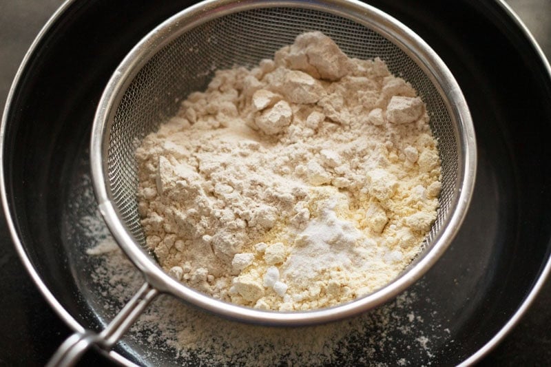 Sifting whole wheat flour, gram flour and baking soda.