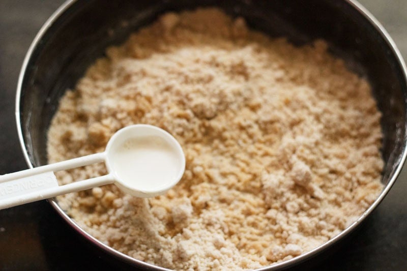Milk in a tablespoon being added to flour and sugar mix.