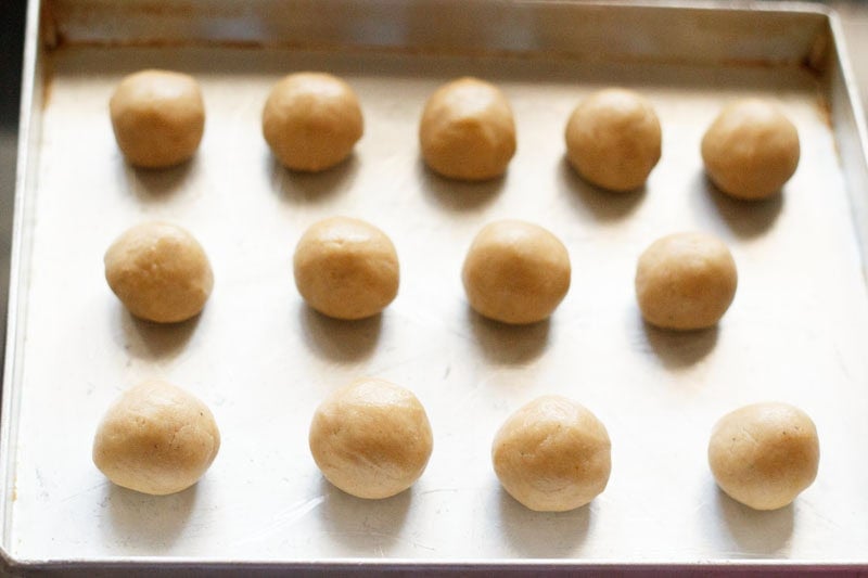 Balls of wheat cookie dough on baking tray.