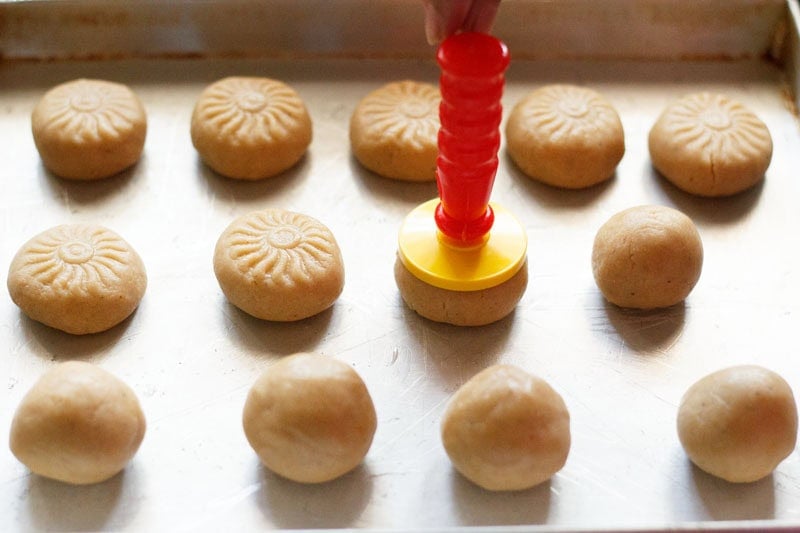 Cookie dough ball being flattened with a cookie press.
