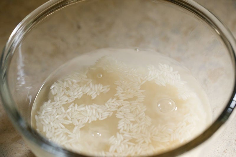 Jasmine rice and water in a glass bowl.