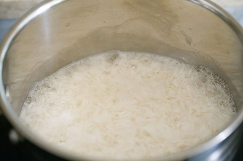 Bubbling water and jasmine rice in pan.