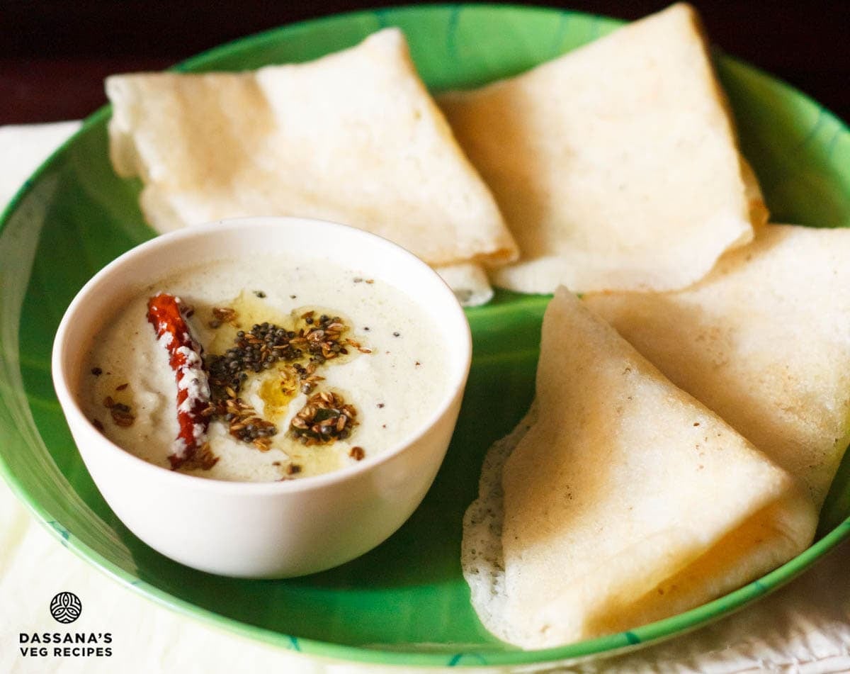 Idli chutney or dosa chutney in a bowl with soft dosas on a plate.
