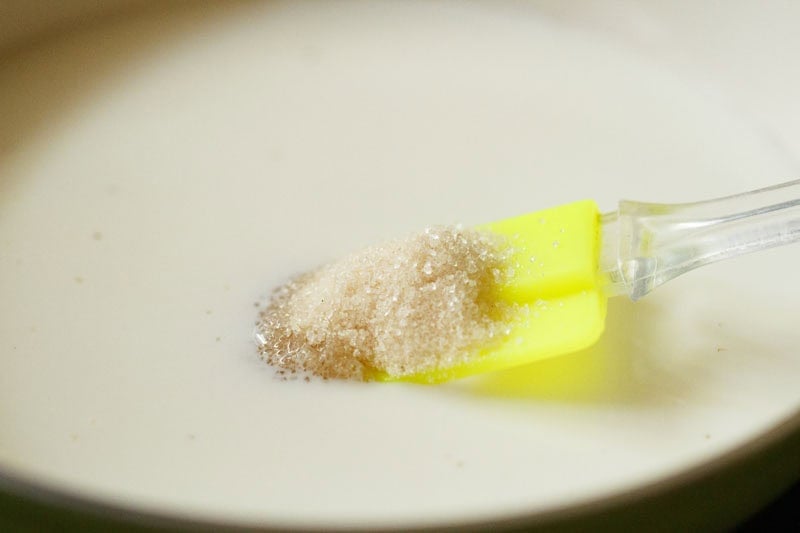 Milk and sugar in a pan with spatula.