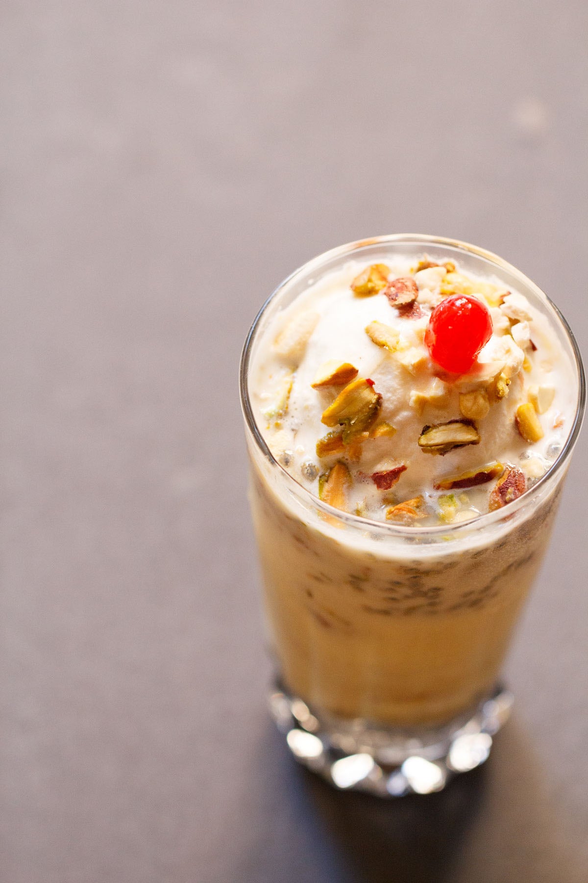 Kesar pista falooda topped with nuts and cherry.