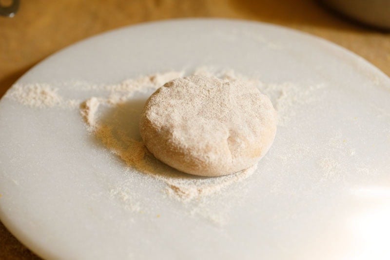 Slightly flattened stuffed dough dusted with flour on a surface.