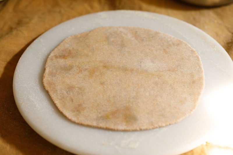 Rolled uncooked sattu paratha on a surface.