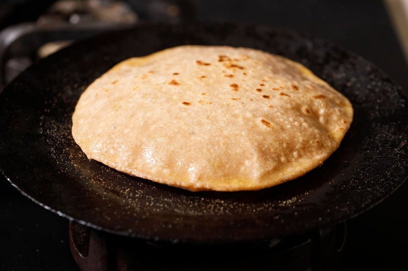 Golden-brown and puffed sattu paratha on a skillet.