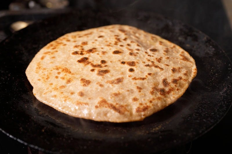 Golden brown sattu paratha on hot skillet.