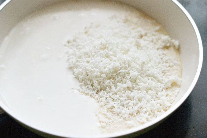 Condensed milk, cream and grated paneer in a pan.