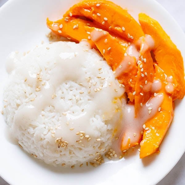 Thai style mango sticky rice sprinkled with sesame seeds.