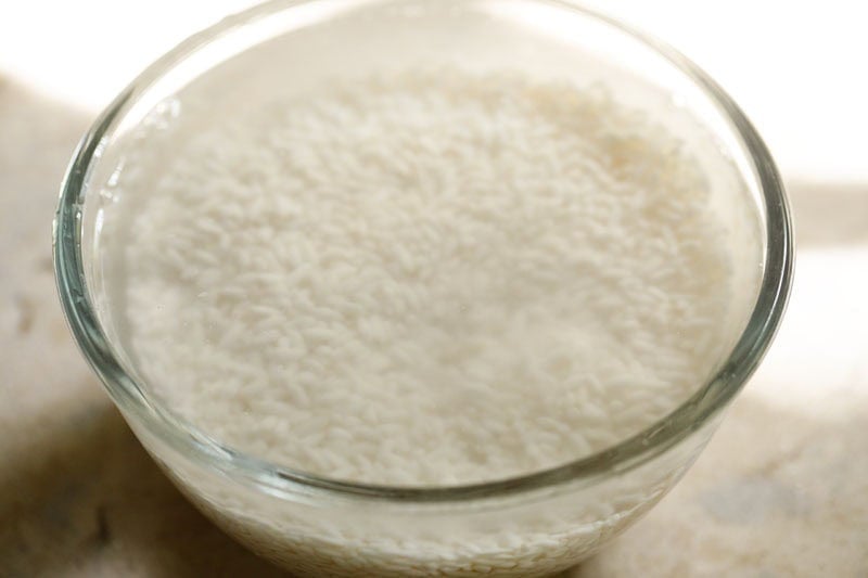 Thai sticky rice soaking in hot water in bowl.