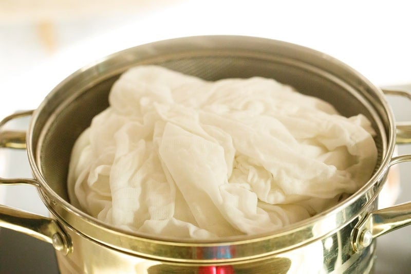 Steamer with sticky rice inside a folded muslin on steaming pot.