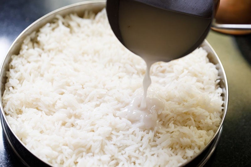 Coconut milk being added to cooked rice.