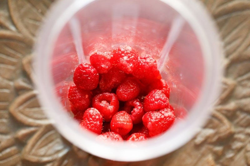 Fresh raspberries in a blender cup.