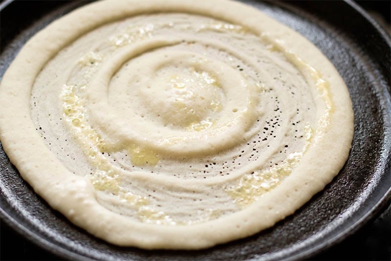 Oil drizzled on cooked rice dosa.