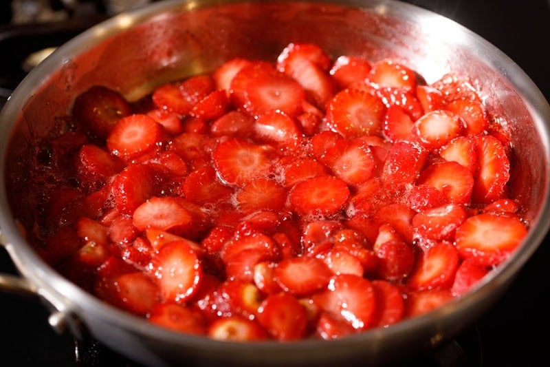 Strawberries mixed with sugar in pan.