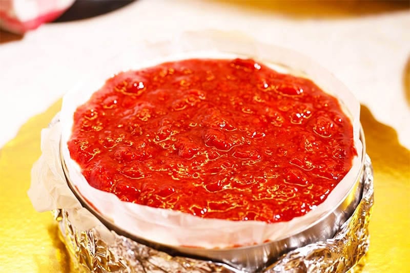 Strawberry coulis spread on top of cheesecake.