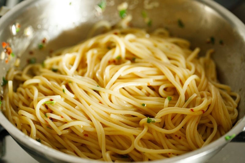 Cooked spaghetti mixed with herbs and spices oil mixture to make aglio e olio.