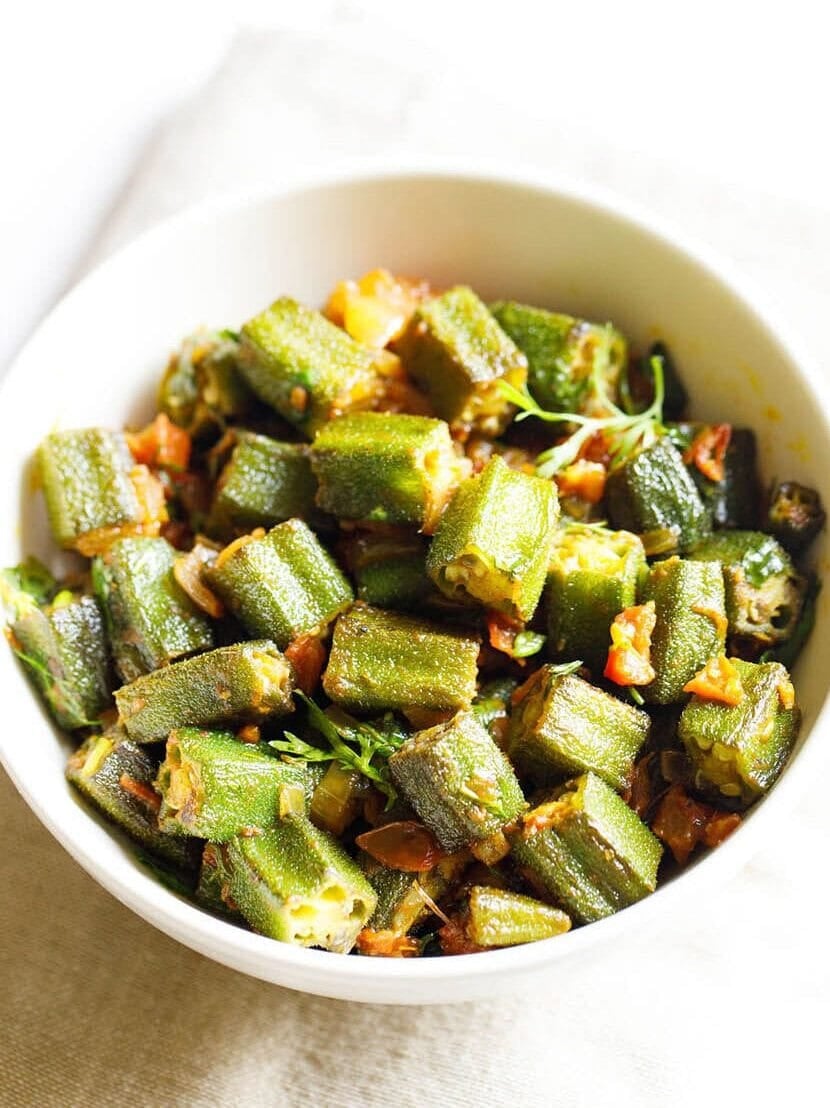 bhindi masala served in a white bowl on an off white napkin on a white background.