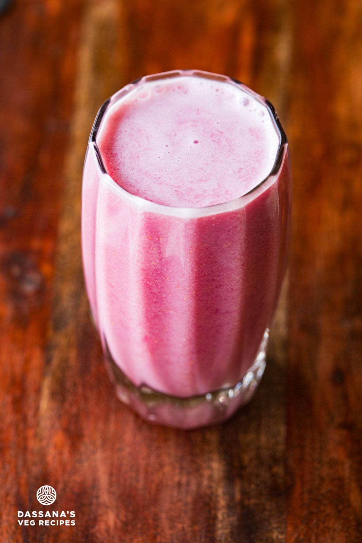 Pomegranate juice in a glass on a wooden board.